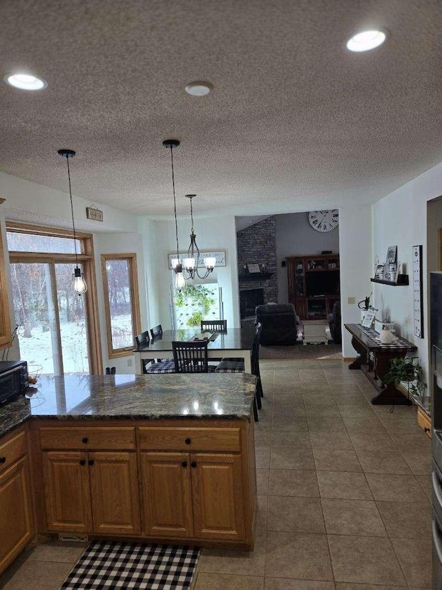 kitchen with brown cabinetry, decorative light fixtures, and plenty of natural light