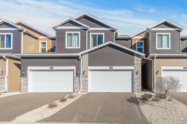 view of front facade featuring stone siding, driveway, and an attached garage