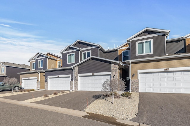 view of property featuring stone siding, an attached garage, and driveway