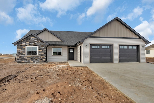 view of front of home with concrete driveway, an attached garage, stone siding, and roof with shingles