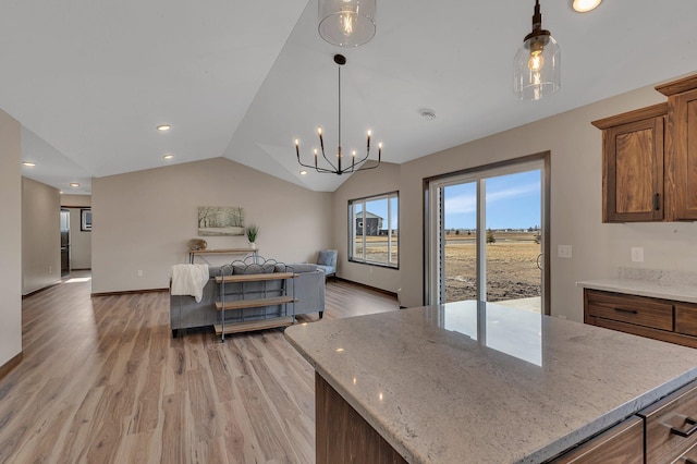 interior space featuring brown cabinetry, light wood-type flooring, lofted ceiling, pendant lighting, and open floor plan