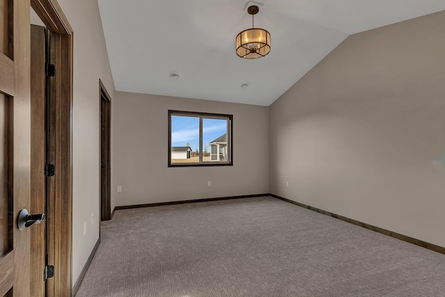 spare room featuring carpet flooring, baseboards, and lofted ceiling