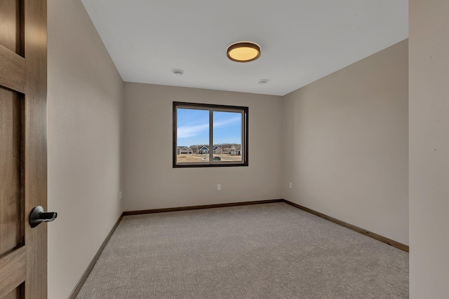 spare room featuring light colored carpet and baseboards