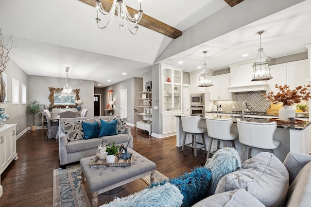 living area featuring lofted ceiling with beams, baseboards, dark wood-style flooring, and a chandelier