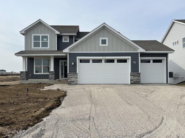 craftsman inspired home featuring stone siding, board and batten siding, an attached garage, and a shingled roof