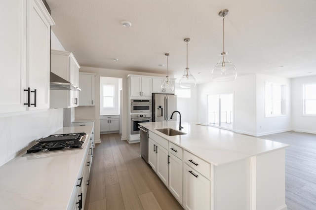 kitchen featuring light countertops, appliances with stainless steel finishes, an island with sink, and a sink