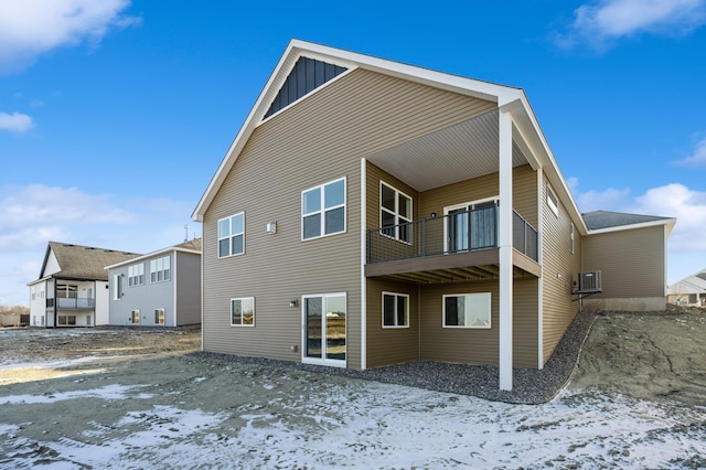 snow covered back of property featuring board and batten siding and a balcony