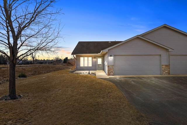 view of front of home featuring aphalt driveway, roof with shingles, and an attached garage