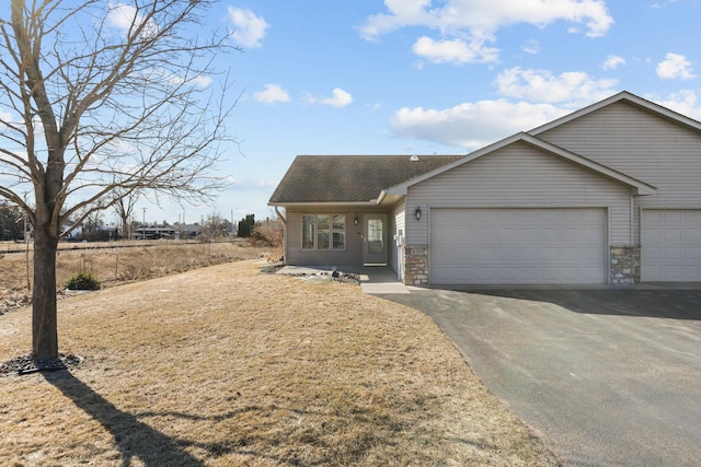 ranch-style house with stone siding, driveway, an attached garage, and roof with shingles