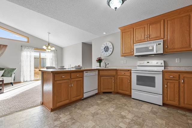 kitchen with brown cabinetry, an inviting chandelier, white appliances, and a peninsula