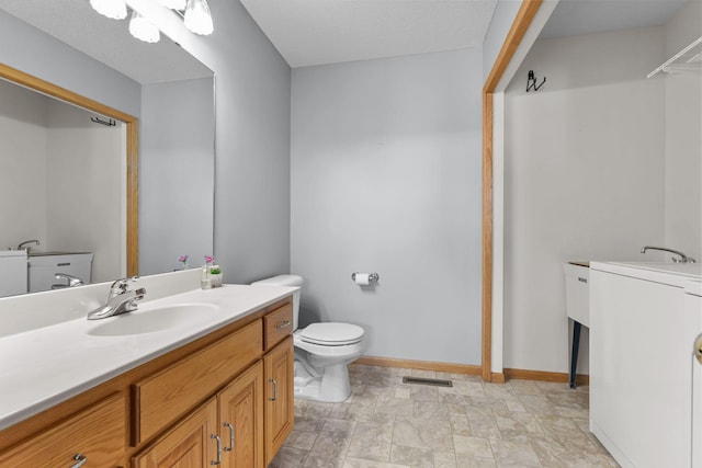 full bath with visible vents, baseboards, toilet, vanity, and washer / clothes dryer