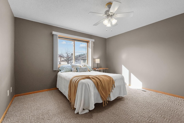 bedroom featuring light carpet, a textured ceiling, baseboards, and a ceiling fan