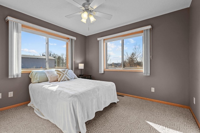 bedroom with a ceiling fan, light colored carpet, and baseboards