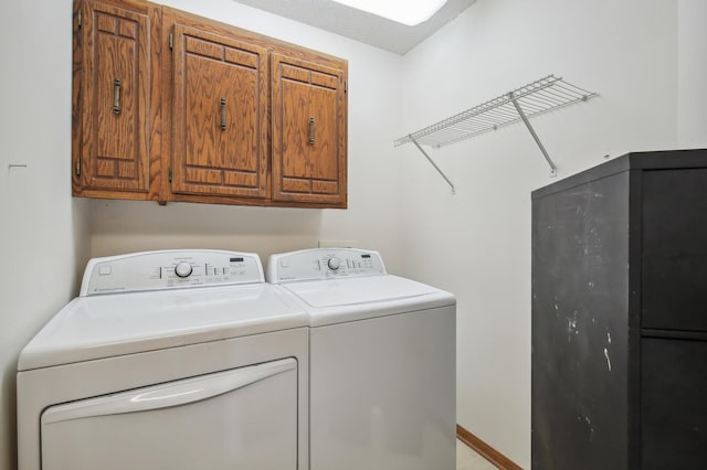 washroom with cabinet space, washing machine and dryer, and baseboards