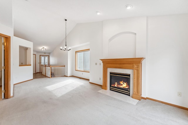 unfurnished living room featuring high vaulted ceiling, light colored carpet, a high end fireplace, a chandelier, and baseboards