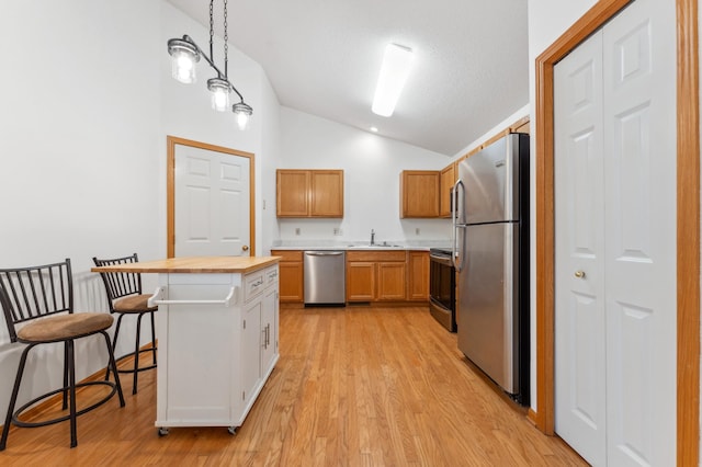 kitchen with a kitchen island, appliances with stainless steel finishes, decorative light fixtures, light countertops, and a sink