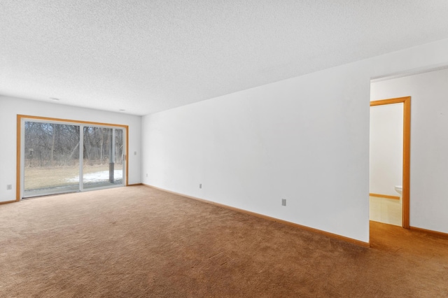 spare room with carpet floors, baseboards, and a textured ceiling