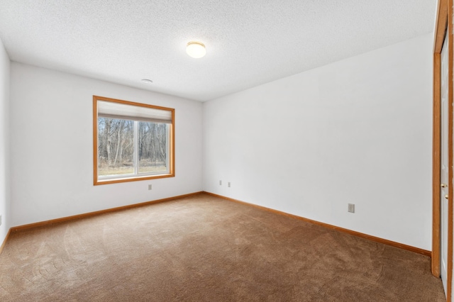 carpeted spare room with a textured ceiling and baseboards