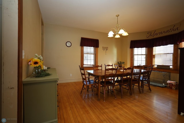 dining area with light wood-style floors, a notable chandelier, and baseboards