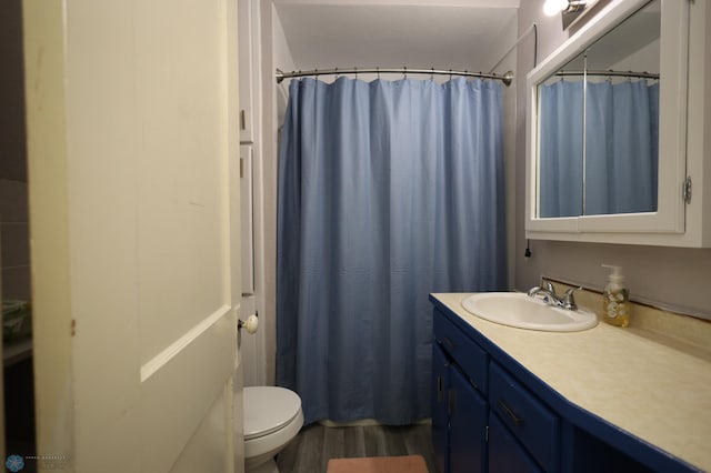 bathroom featuring toilet, wood finished floors, and vanity