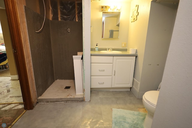 bathroom featuring toilet, tile patterned flooring, a tile shower, and vanity