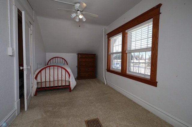 unfurnished bedroom with baseboards, visible vents, a ceiling fan, light colored carpet, and lofted ceiling