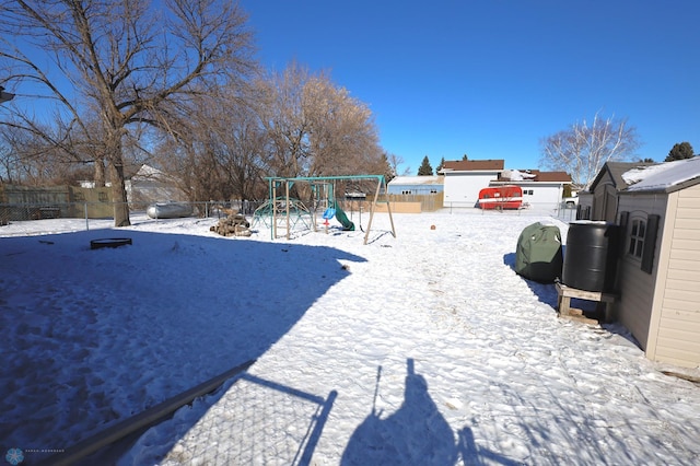 snowy yard featuring a playground and fence