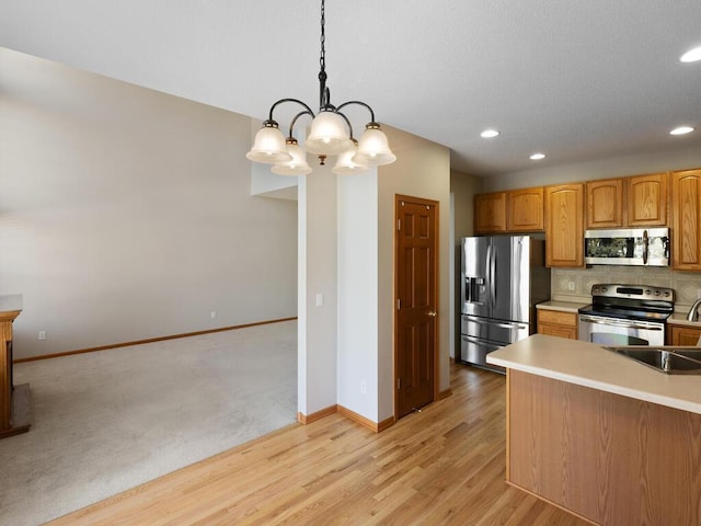 kitchen with brown cabinets, stainless steel appliances, tasteful backsplash, light countertops, and hanging light fixtures