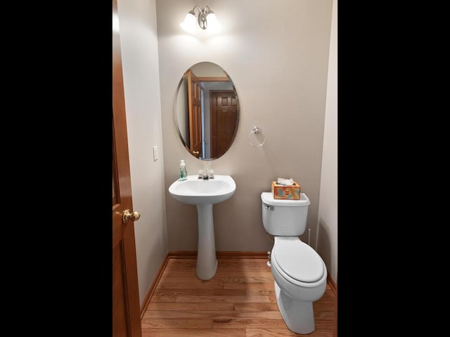 bathroom featuring toilet, baseboards, and wood finished floors