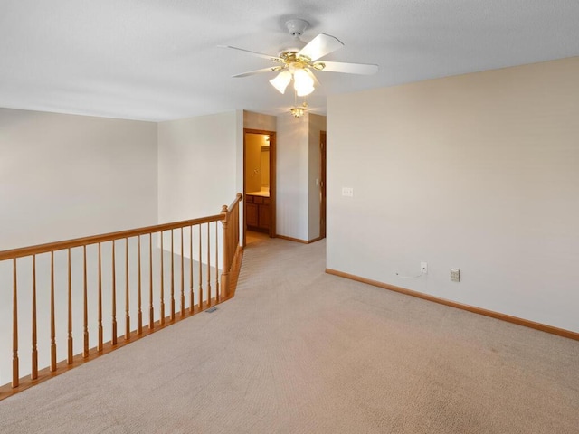 spare room with light carpet, ceiling fan, and baseboards