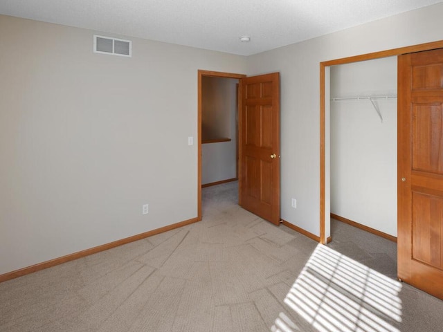 unfurnished bedroom with baseboards, visible vents, a closet, and light colored carpet