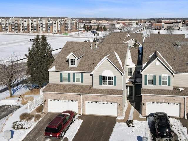 view of front facade with roof with shingles, brick siding, a garage, a residential view, and driveway