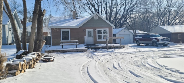 bungalow-style home with a detached garage, a chimney, and an outbuilding