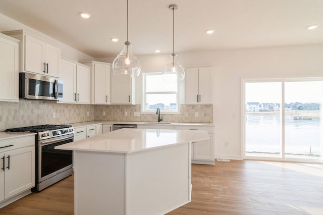 kitchen featuring appliances with stainless steel finishes, light countertops, a sink, and white cabinetry