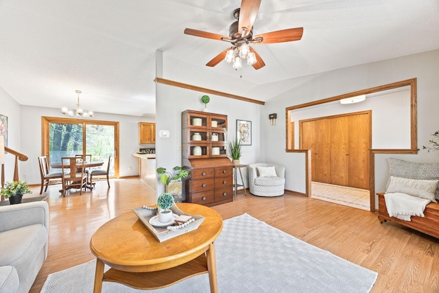 living area with a chandelier, light wood-style floors, a ceiling fan, vaulted ceiling, and baseboards