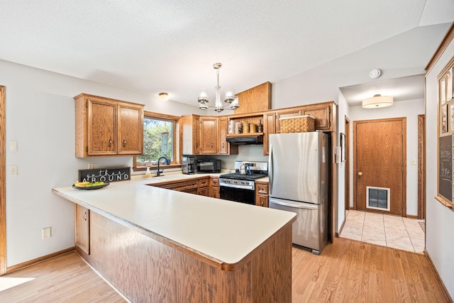 kitchen with appliances with stainless steel finishes, under cabinet range hood, a peninsula, light countertops, and a chandelier