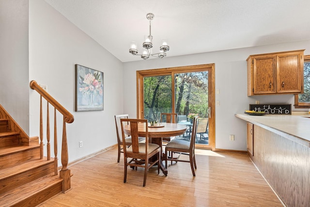 dining space with light wood-style flooring, a chandelier, stairway, lofted ceiling, and baseboards