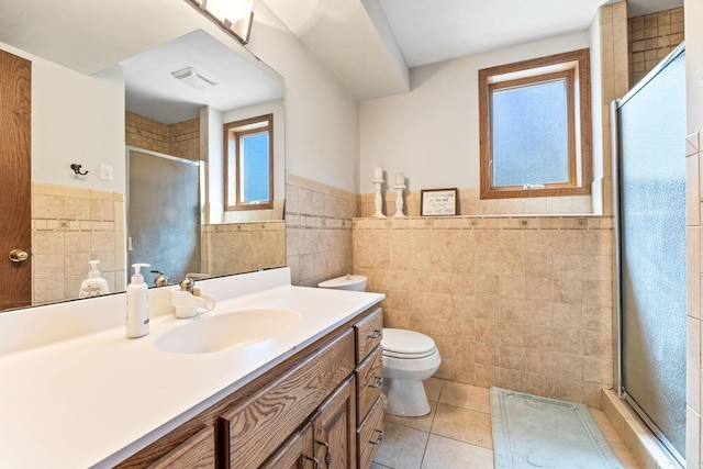 bathroom featuring tile walls, a shower stall, tile patterned flooring, wainscoting, and toilet