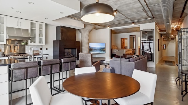 dining room featuring finished concrete flooring, a glass covered fireplace, and recessed lighting