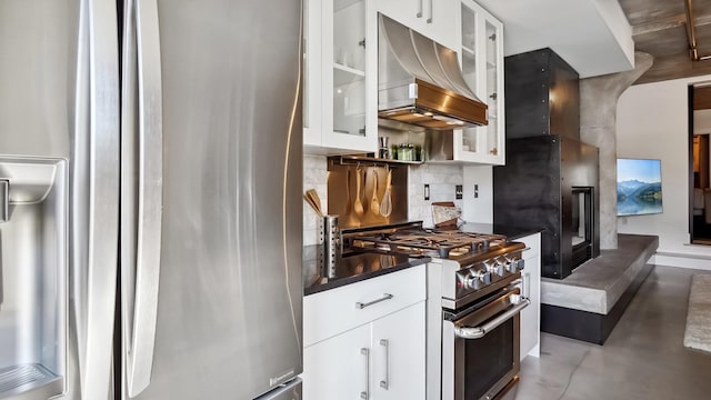 kitchen with range hood, stainless steel appliances, dark countertops, decorative backsplash, and white cabinets