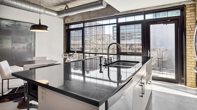 kitchen with white dishwasher, a sink, white cabinetry, dark countertops, and decorative light fixtures