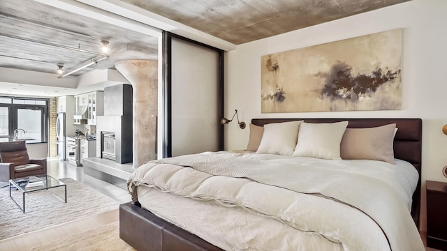 bedroom featuring a sink, access to outside, wood finished floors, and freestanding refrigerator