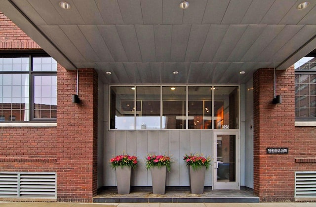 property entrance with brick siding and visible vents