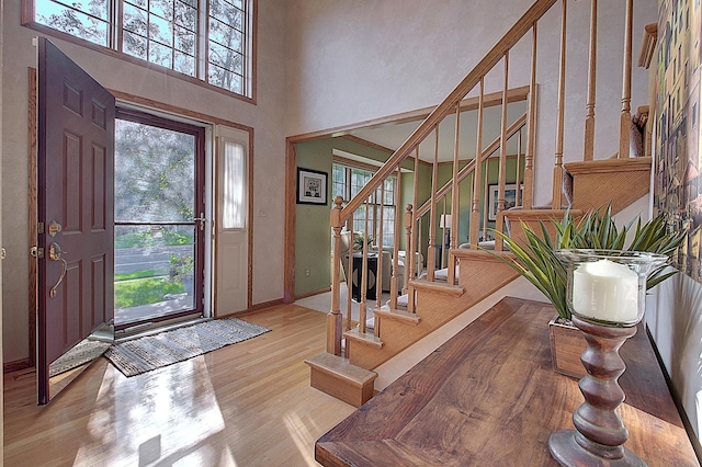 entryway with stairway, a healthy amount of sunlight, light wood-style flooring, and a high ceiling