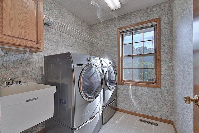 laundry area with cabinet space, wallpapered walls, visible vents, washer and dryer, and a sink