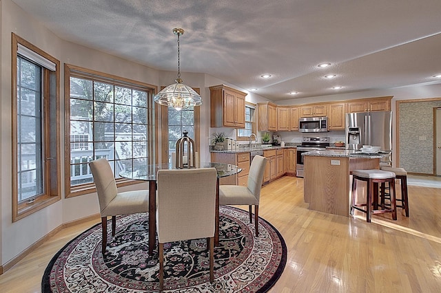 dining space featuring baseboards, a textured ceiling, light wood-style floors, a chandelier, and recessed lighting