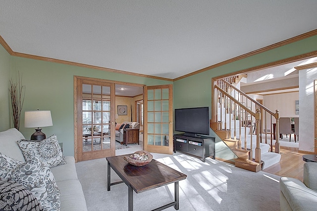 living area with a textured ceiling, light wood-style flooring, stairs, french doors, and ornamental molding