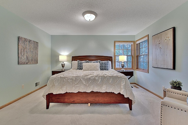 bedroom with visible vents, light carpet, baseboards, and a textured ceiling