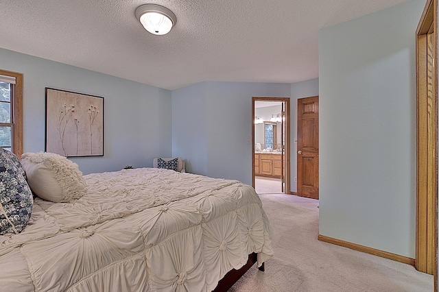 bedroom with baseboards, a textured ceiling, ensuite bathroom, and light colored carpet