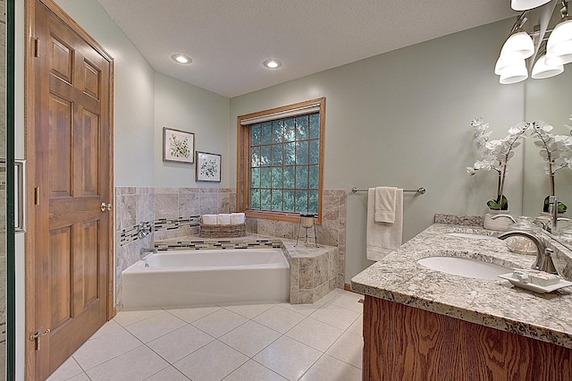 full bath with double vanity, a garden tub, tile patterned flooring, a textured ceiling, and a sink